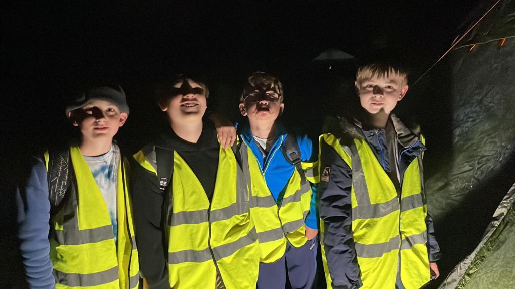 Four boy scouts in high vis vests in the dark