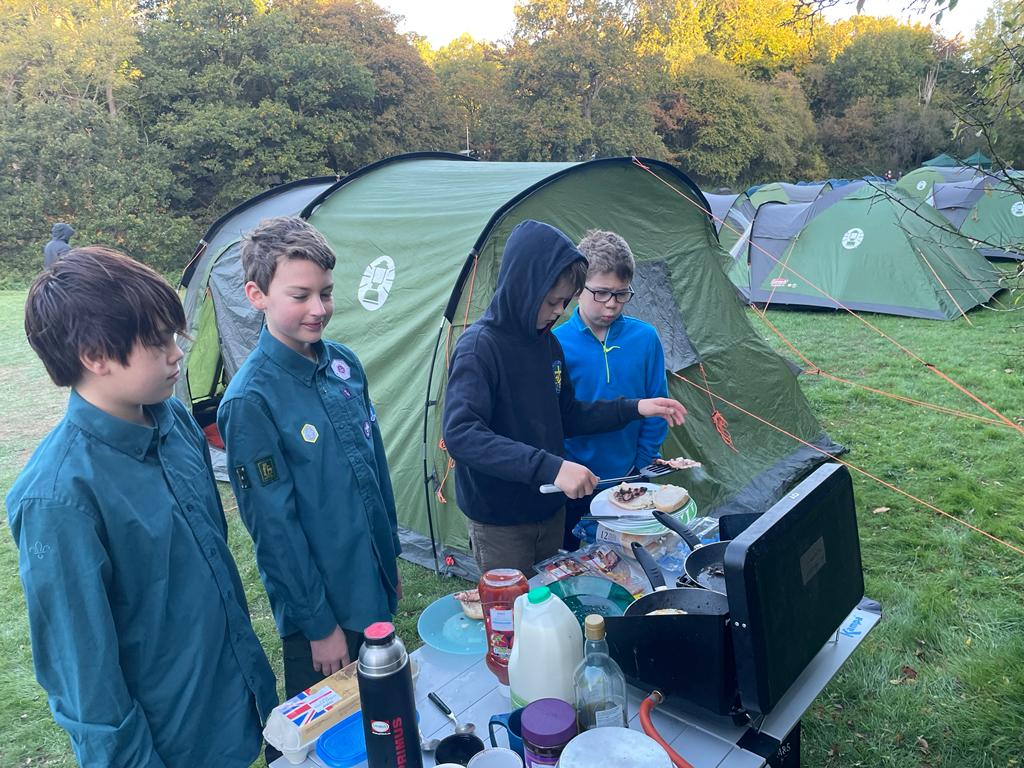 Four boys cooking on a camping stove