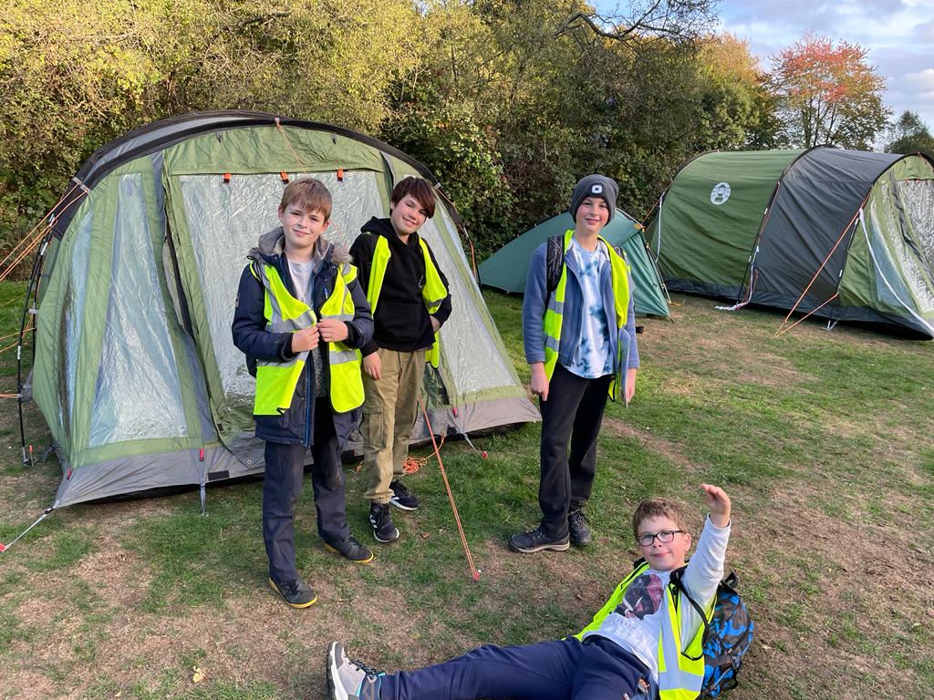 Four boys stood in front of a tent in walking gear.